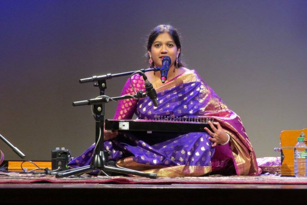 Mouli Chakrabarti performing with a lap instrument and microphone in Berlin.