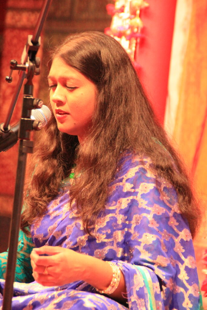 Close view of Mouli Chakrabarti singing with her eyes closed at a microphone in Kassel.