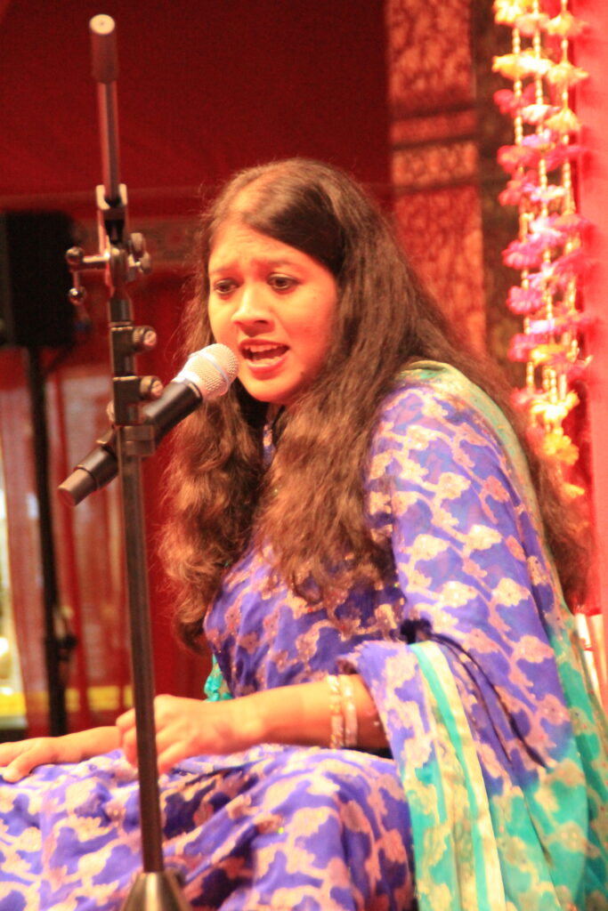 Mouli Chakrabarti singing into a microphone during a concert in Kassel.